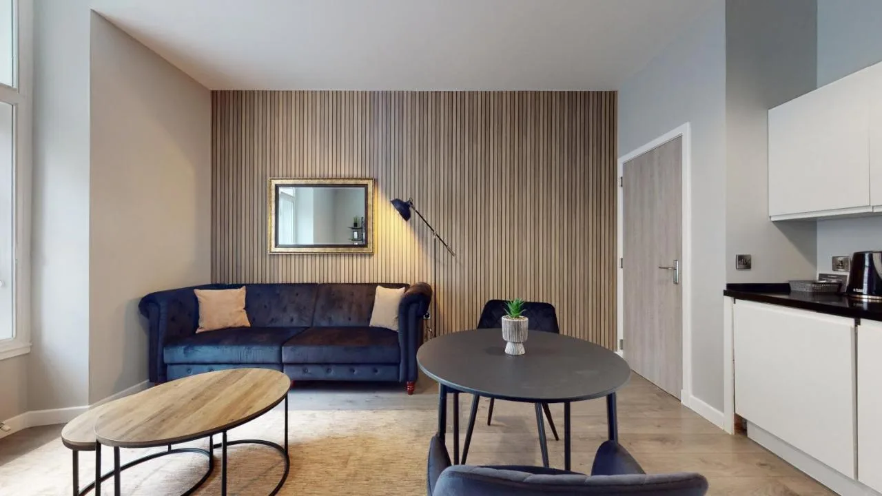 A living room with a blue couch and table at Glassford Residence in Glasgow